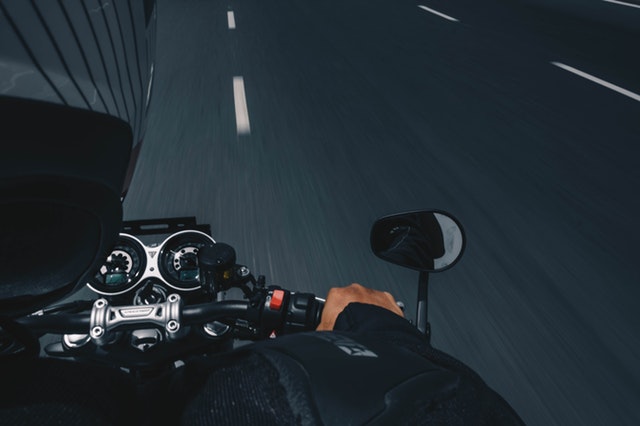 Muž s prilbou idúci na motorke po ceste