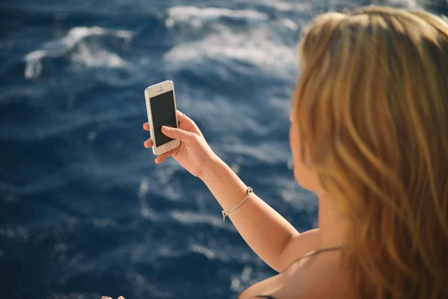 Žena s mobilom pri mori